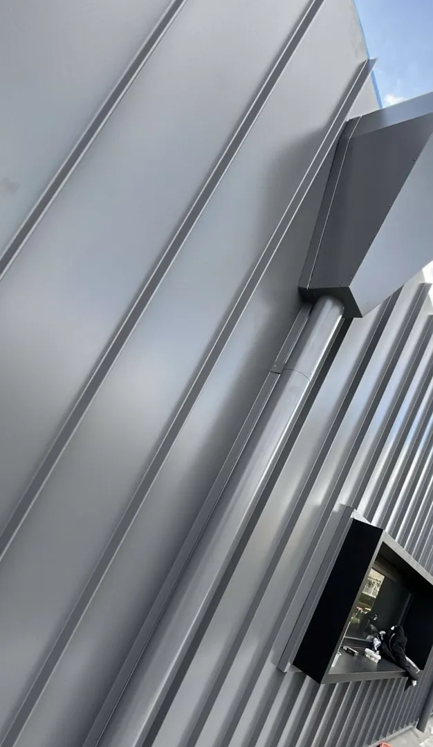 Modern gray corrugated metal wall with vent system.