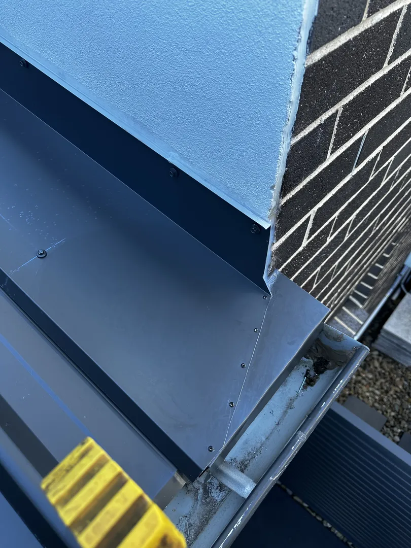 Roof flashing detail near brick and stucco wall.